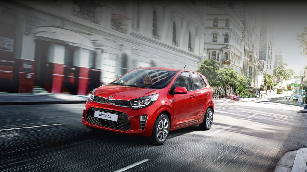 Roter Kleinwagen fährt dynamisch durch die Stadtstraße