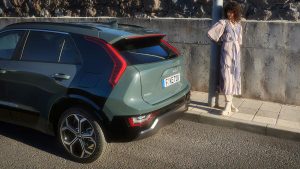 Frau steht neben einem modernen grünen SUV auf der Straße