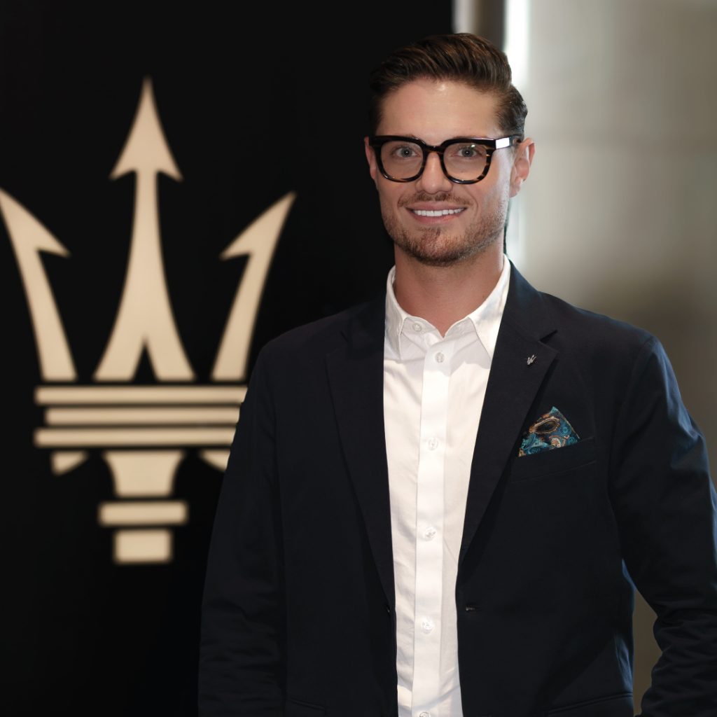 Eleganter Mann vor Luxusautologo in moderner Kleidung