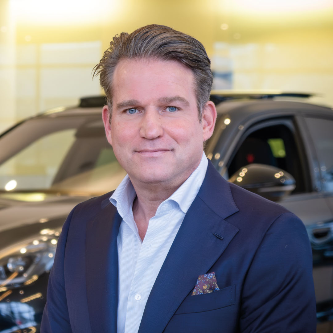 Geschäftsmann vor einem modernen Auto in formeller Kleidung