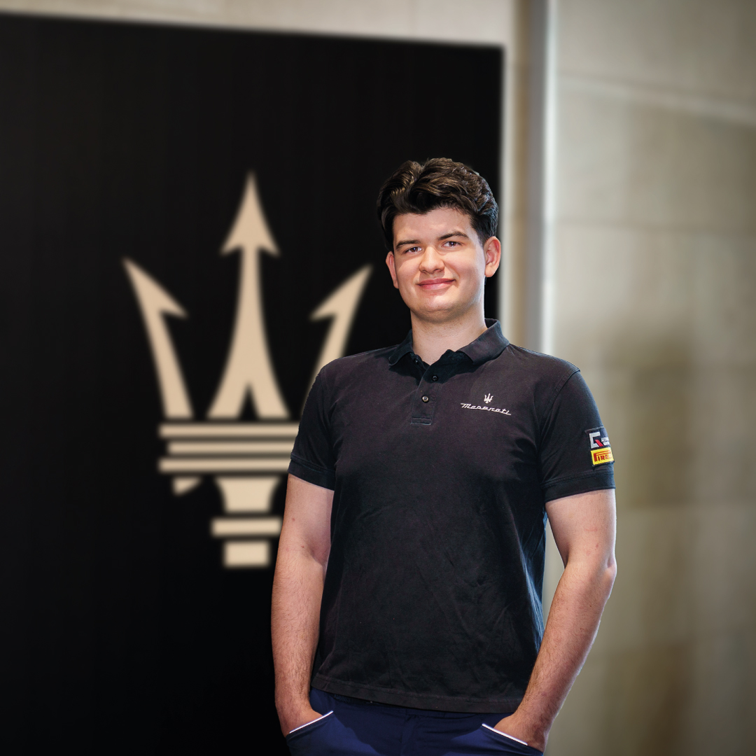 Junger Mann vor Maserati Logo in modernem Ausstellungsraum