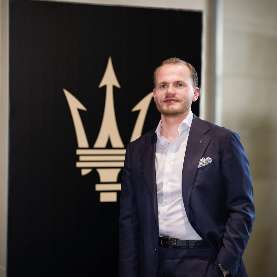 Ein Mann im Anzug steht vor einem großen Firmenlogo