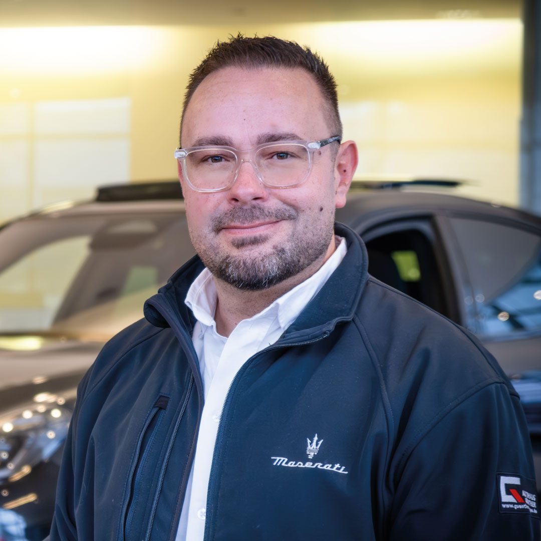 Mann in Maserati-Jacke steht vor einem Auto im Schauraum