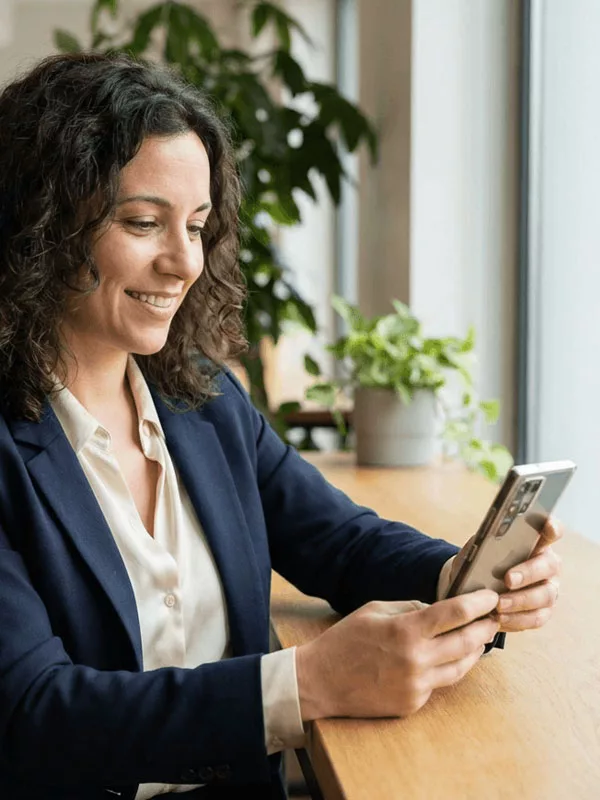 Geschäftsfrau am Schreibtisch mit Smartphone in der Hand