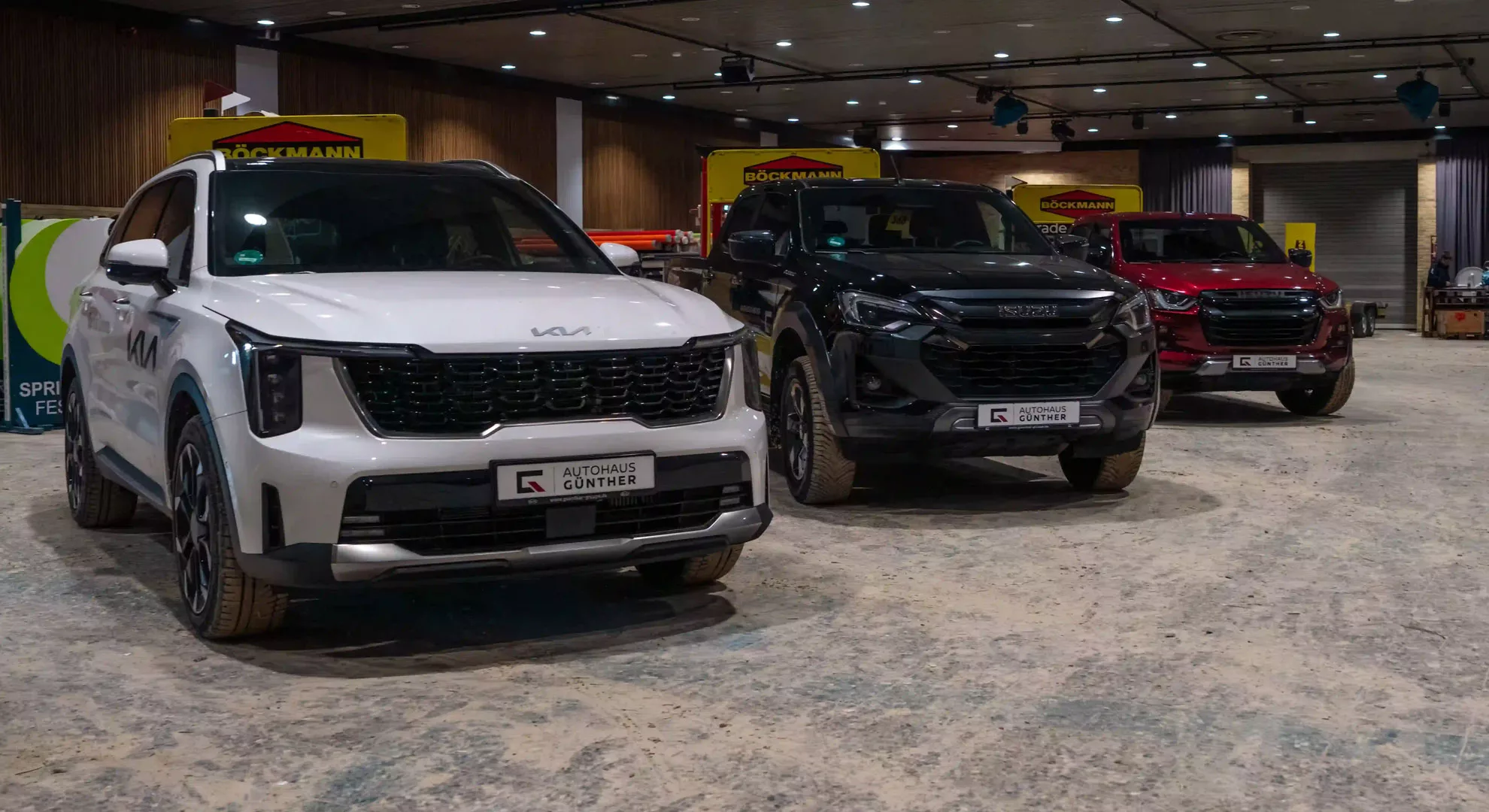 Drei moderne SUVs auf einer Autoausstellung in heller Halle